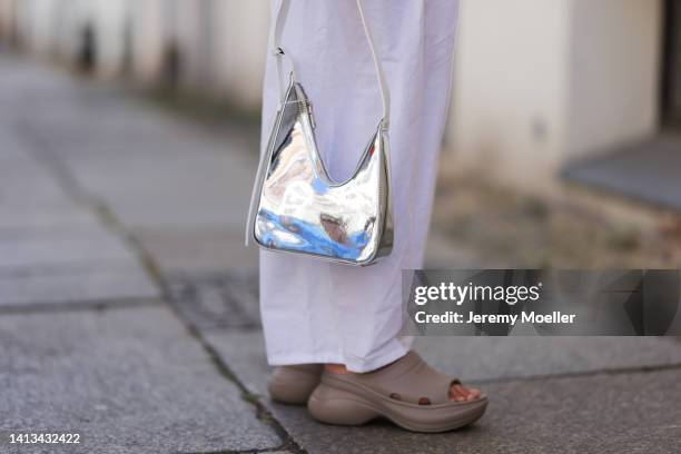 Anna Winter wearing Balenciaga x Crocs Pool Slide beige Sandal, Source Unknown white loose pants, Source Unknown silver shiny hobo bag on August 06,...