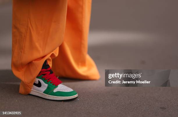 Karin Teigl wearing COS orange wide leg pants, Nike Air Jordan green white red sneaker on August 04, 2022 in Vienna, Austria.