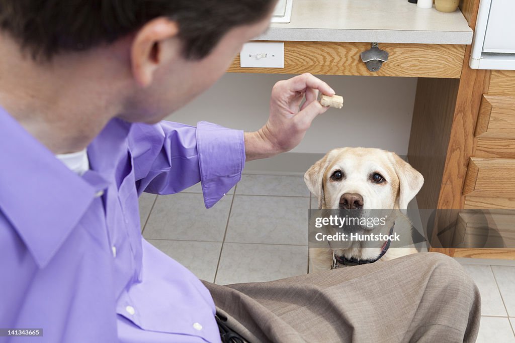 Man with spinal cord injury offering a treat to his service dog