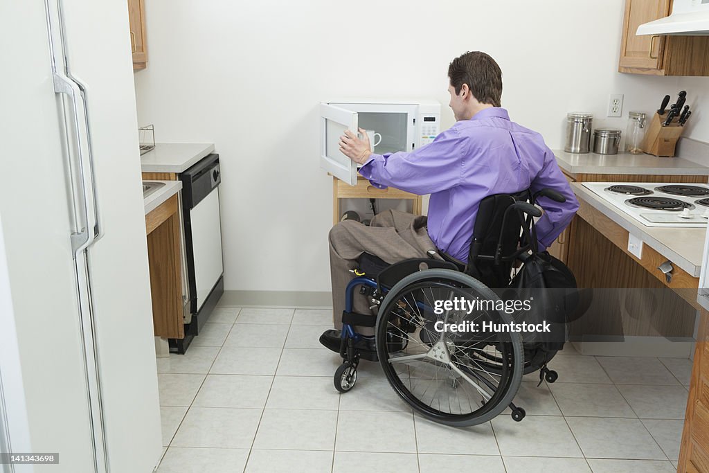 Man in wheelchair with spinal cord injury opening accessible microwave