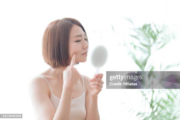 woman looking in the mirror - caratteristica della pelle foto e immagini stock
