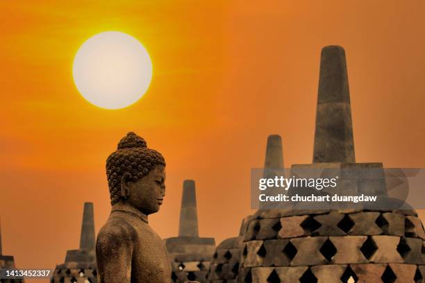 buddha statue and sunset over in borobudur - borobudur temple stock pictures, royalty-free photos & images
