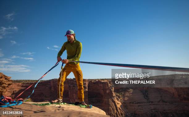 young guy double check the ropes for slack lining - looking over cliff stock pictures, royalty-free photos & images
