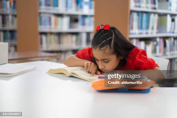 girl with myopia reading and following close with finger - eyesight problem stock pictures, royalty-free photos & images