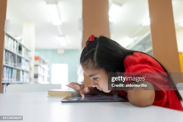 shortsighted little girl using tablet with face close to screen - myopia 個照片及圖片檔