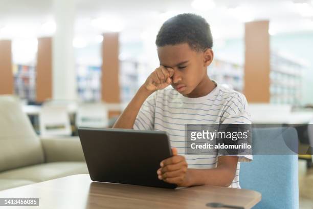 little boy holding tablet and rubbing his eyes - eyesight problem stock pictures, royalty-free photos & images