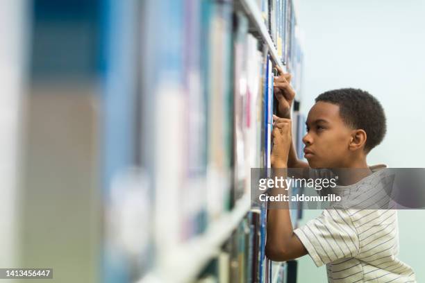 menino com miopia em busca de livro em estantes - deficiência visual - fotografias e filmes do acervo