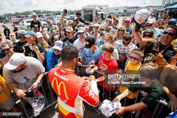 Bubba Wallace, driver of the McDonald's Toyota, signs autographs for young NASCAR fans prior to the NASCAR Cup Series FireKeepers Casino 400 at...