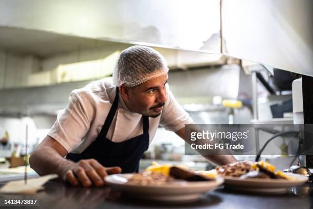 chef putting orders on the counter - haarnet stockfoto's en -beelden