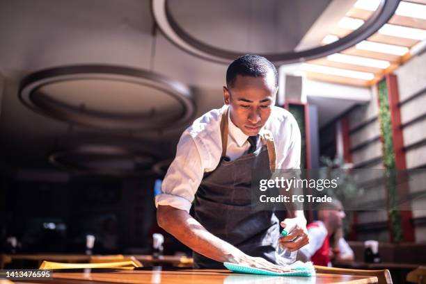 waiter cleaning a dining table at a restaurant - restaurant atmosphere stock pictures, royalty-free photos & images