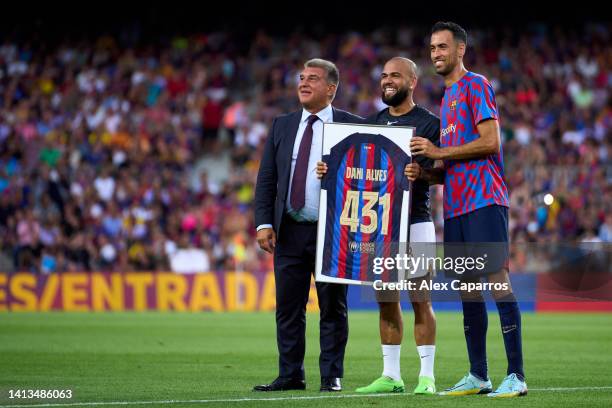 Dani Alves of Pumas UNAM poses alongside President Joan Laporta and Sergio Busquets of FC Barcelona with a FC Barcelona jersey with the '431' number...