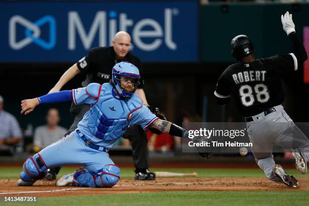 Luis Robert of the Chicago White Sox scores a run in the fourth inning as Jonah Heim of the Texas Rangers cannot catch the throw at Globe Life Field...