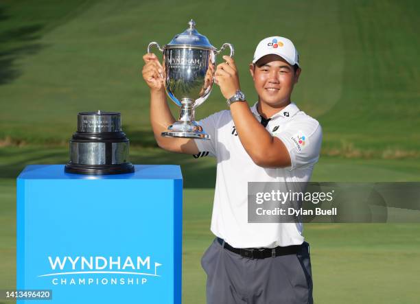 Joohyung Kim of Korea poses with the trophy after putting in to win on the 18th green during the final round of the Wyndham Championship at...