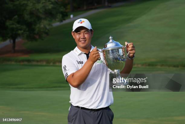 Joohyung Kim of Korea poses with the trophy after putting in to win on the 18th green during the final round of the Wyndham Championship at...