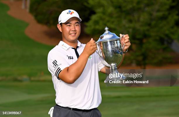 Joohyung Kim of Korea poses with the trophy after putting in to win on the 18th green during the final round of the Wyndham Championship at...