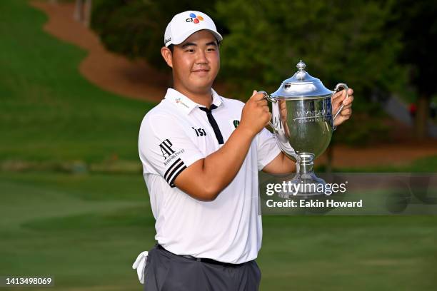 Joohyung Kim of Korea poses with the trophy after putting in to win on the 18th green during the final round of the Wyndham Championship at...