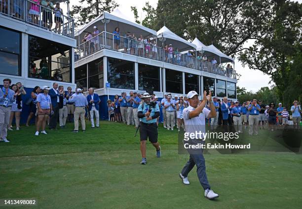 Joohyung Kim of Korea walks back onto the 18th green to receive the trophy after putting in to win during the final round of the Wyndham Championship...
