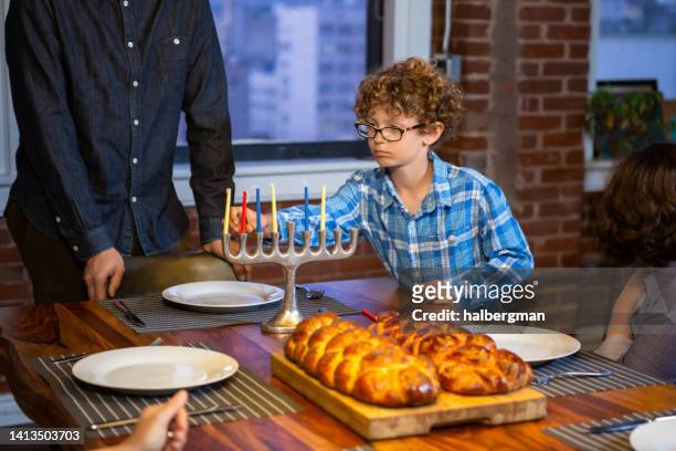 child placing candles for hanukkah - jewish sabbath stock pictures, royalty-free photos & images
