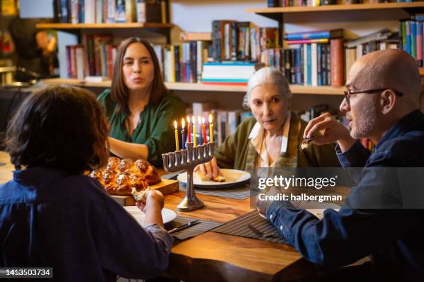 family eating challah on hanukkah - jewish sabbath stock pictures, royalty-free photos & images