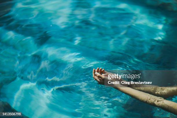 woman hands on clear turquoise water surface. copy space background - swimming pool and hand stock pictures, royalty-free photos & images