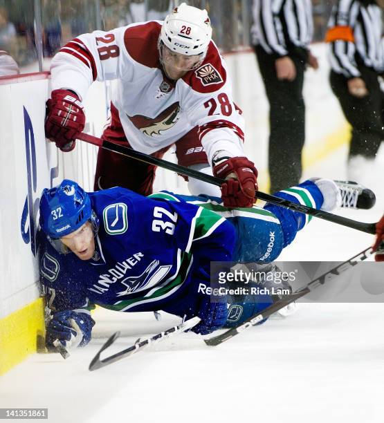 Dale Weise of the Vancouver Canucks is knocked down to the ice by Lauri Korpikoski of the Phoenix Coyotes during the second period in NHL action on...