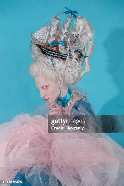 renaissance princess with blonde hair on blue background. beauty makeup. fairytale rococo queen with ship in hairstyle in studio. model in blue dress. woman with historical hair style - countess stock pictures, royalty-free photos & images