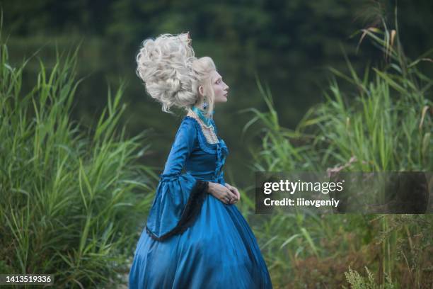 renaissance princess with blonde hair on lake background. beauty makeup. fairytale rococo queen with ship in hairstyle on nature. model in blue dress. woman with historical hair style on bridge - victorian dress stock pictures, royalty-free photos & images