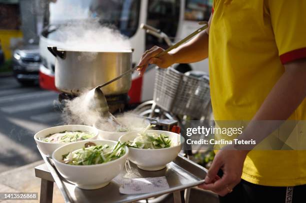 hands pouring broth into bowls of pho - vietnam and street food stock pictures, royalty-free photos & images