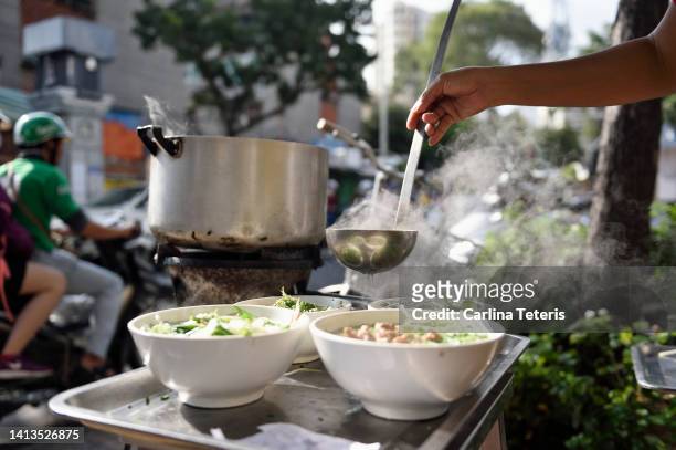 hands pouring broth into bowls of pho - vietnamese food stock-fotos und bilder