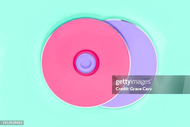 pink and purple cds on green background - dvd stock pictures, royalty-free photos & images