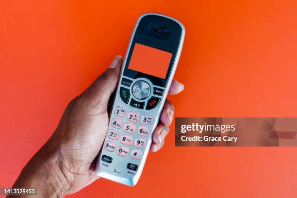 woman holds cordless landline phone handset - festnetzanschluss stock-fotos und bilder