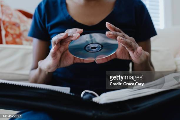 woman selects cd from her collection - cdケース ストックフォトと画像