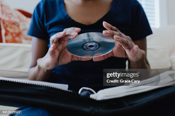 woman selects cd from her collection - cd imagens e fotografias de stock