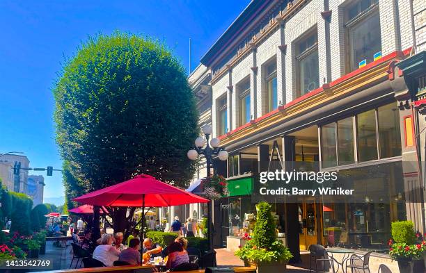 people dining on street below umbrella, victoria - victoria canada dining stock pictures, royalty-free photos & images