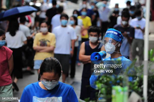 Medical worker holding a megaphone keeps order as residents queue up for COVID-19 nucleic acid tests on August 7, 2022 in Sanya, Hainan Province of...
