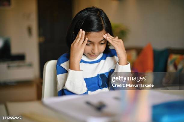 girl sitting with her hands on head while studying - astigmatismo imagens e fotografias de stock