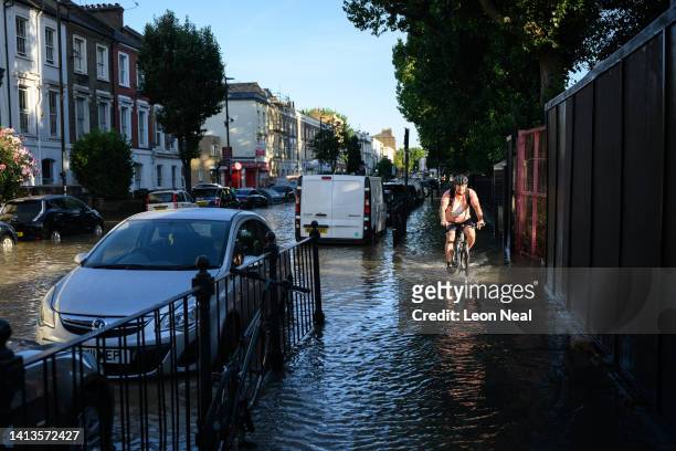 Cyclist negotiates the substantial flooding on roads near to the Arsenal Stadium, following a rupture of water mains, on August 08, 2022 in London,...