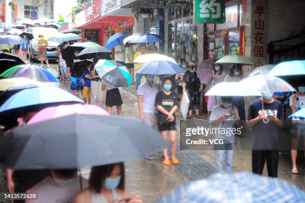 Residents queue up in rain for COVID-19 nucleic acid tests on August 8, 2022 in Sanya, Hainan Province of China.