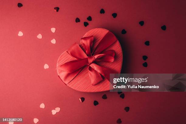 red gift box heart shape with red ribbon on a red background. - gift box tag stock-fotos und bilder