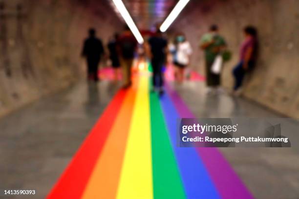 blurred tunnel pathway illuminated in the pride flag colors - backgrounds people stock-fotos und bilder