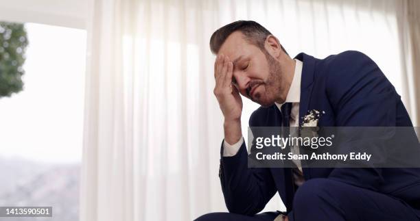 stressed, sad and unhappy man with emotional expression on the morning of his wedding looking heart broken, disappointed and depressed. husband to be sitting alone with guilt from a breakup or affair - a posh affair stock pictures, royalty-free photos & images