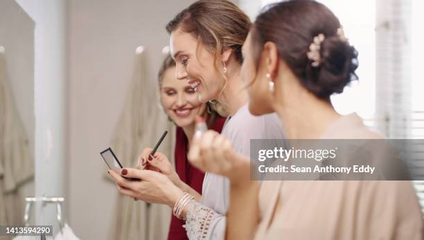 group of happy, beautiful and elegant bridesmaid women getting ready, applying makeup and dressing in the bathroom for a wedding. modern young and pretty ladies putting on cosmetics in a mirror - make up stock pictures, royalty-free photos & images