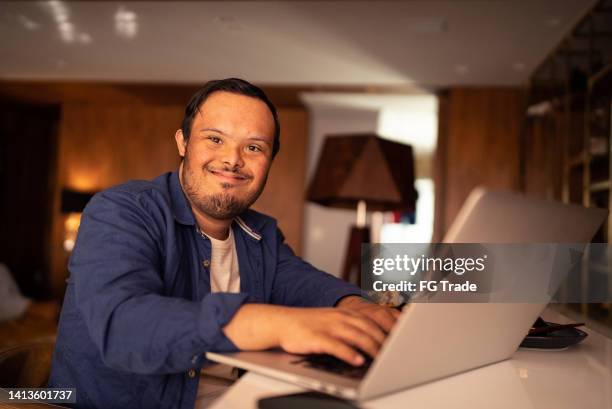 portrait of a young man with special needs using laptop at home - mental disability stock pictures, royalty-free photos & images