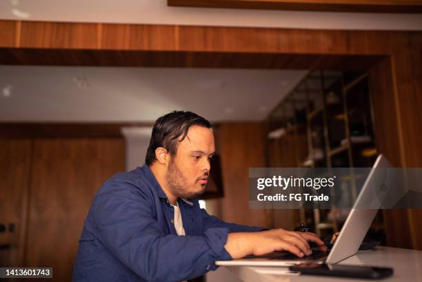 young man with special needs using laptop at home - mental disability stock pictures, royalty-free photos & images