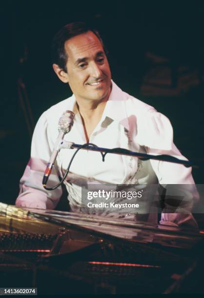 American singer, songwriter and pianist Neil Sedaka sitting at a piano as he performs live in concert, 1986.