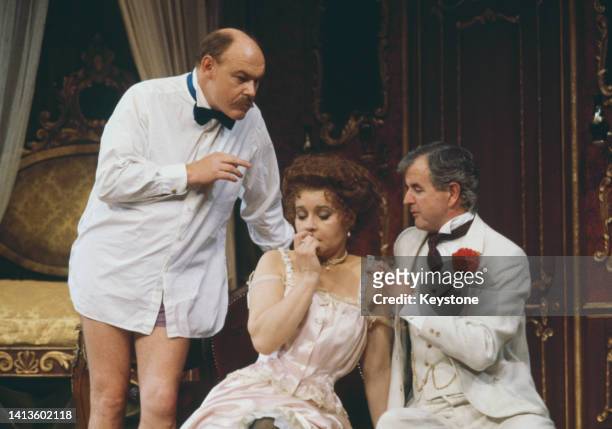 British actor Timothy West, wearing a white shirt with a bow tie and no trousers, with his wife, British actress Prunella Scales, wearing Edwardian...