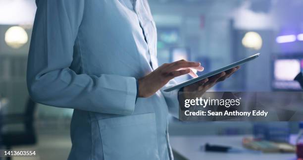 doctor, researcher or scientist browsing the internet on a tablet for information while working at a lab, science facility or hospital. expert, medical professional or surgeon searching the internet - choosing experiment stockfoto's en -beelden