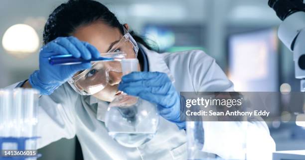 scienziato pensante, concentrato e professionale che fa ricerca per creare una cura in un laboratorio di ricerca. esperto medico che utilizza attrezzature scientifiche in un laboratorio. seria operatrice sanitaria che sperimenta - becher foto e immagini stock