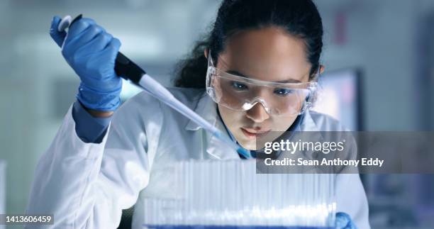 research, experiment and medical trial being done by a scientist in a lab, science facility or hospital. one young, serious and professional researcher organizing, sorting or making a discovery - onderzoeksfaciliteit stockfoto's en -beelden