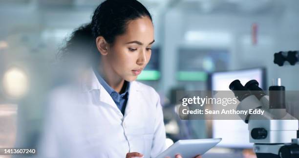 focused and serious science researcher reading information on a tablet in a lab. science student studying data on a handheld tablet in a laboratory while preparing for an experiment. - choosing experiment stockfoto's en -beelden